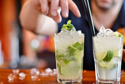 Cropped image of hand over mojito glass on table