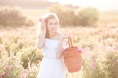 Smiling woman holding flower in basket at farm