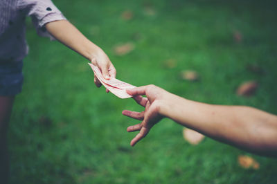 Midsection of woman and man holding money on field