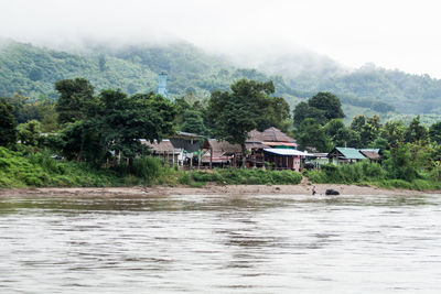 Houses by river against sky