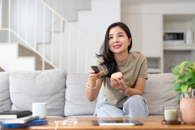 Portrait of young woman using mobile phone while sitting at home