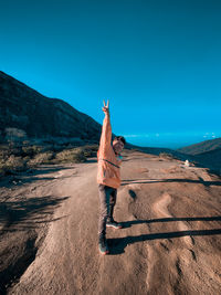 Man standing on mountain road against blue sky
