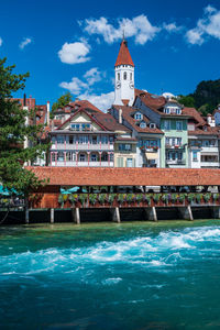 Buildings by river against sky