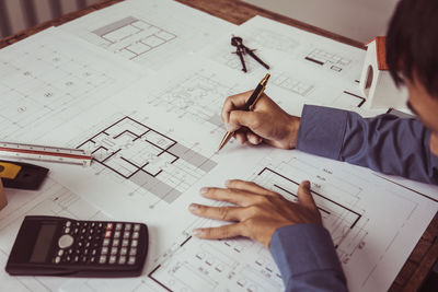 Midsection of businessman working on blueprint