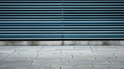 Close-up of sidewalk against closed shutter