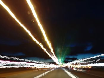 Light trails on road in city against sky at night