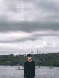 Rear view of man standing against cloudy sky