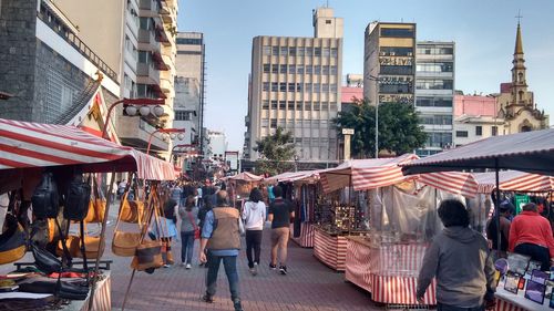 People on street amidst market stalls in city