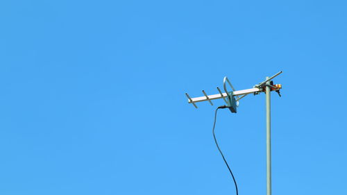 Low angle view of telephone pole against clear blue sky