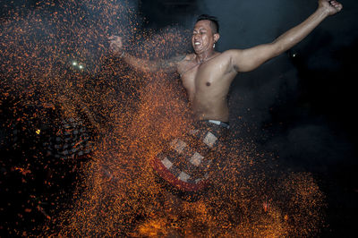 Shirtless man performing stunt with fire at night