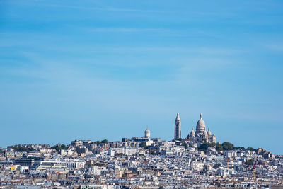 View of buildings in city against blue sky