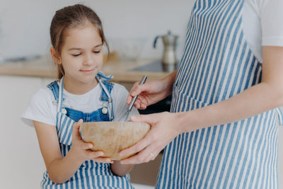 Midsection of mother with daughter preparing food in kitchen