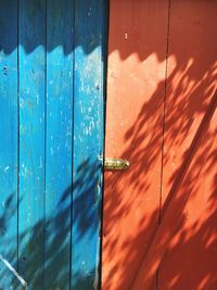 Full frame shot of orange and blue closed door on sunny day