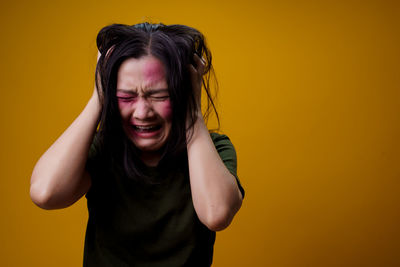 Mid adult woman standing against yellow background