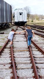 Full length of siblings holding hands on railroad tracks