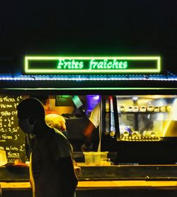 Rear view of man standing in illuminated building