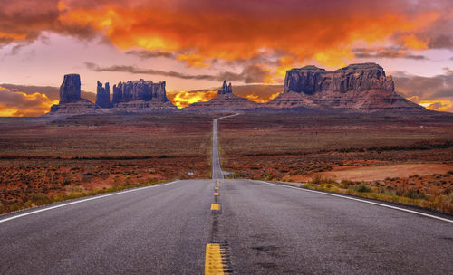 Road leading towards mountains against sky during sunset