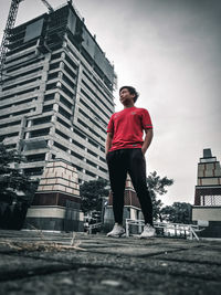 Low angle view of man by building against sky