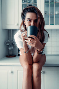 Midsection of woman drinking coffee at home