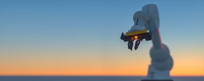 Illuminated machinery against sky during sunset