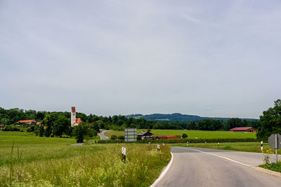 Road amidst field against sky