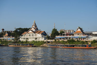 Buildings by river against clear sky