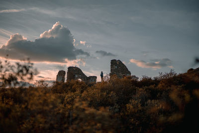 Low angle view of person standing on field against sky during sunset