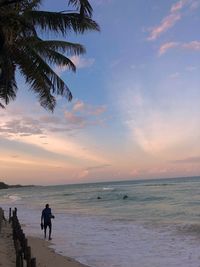 People on beach against sky during sunset