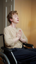 Young man praying while sitting on wheelchair