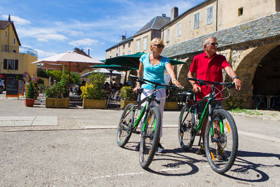 People riding bicycle on street against buildings in city