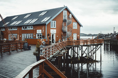 Wooden posts in canal amidst buildings against sky