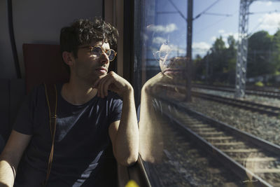 Man traveling by train looking out of window