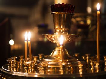 Close-up of illuminated tea light candles on table against building