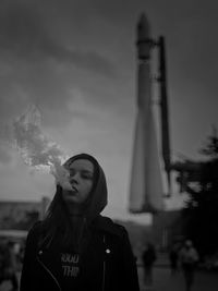 Portrait of woman smoking while standing outdoors