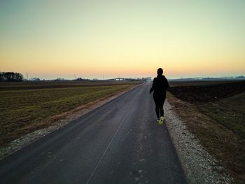 Man on road against sky during sunset