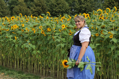 Portrait of woman in dirndl dress standing at sunflower field