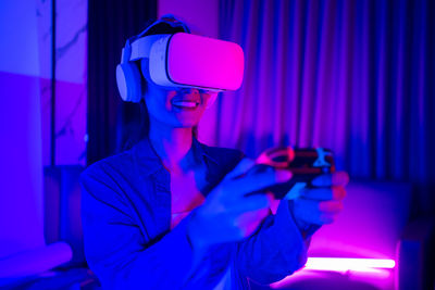 Smiling woman using virtual simulator in illuminated room