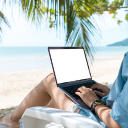 Midsection of man using mobile phone at beach