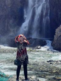 Full length of woman standing against waterfall