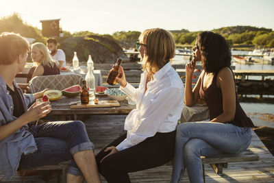 Friends enjoying lunch at picnic table on jetty during summer