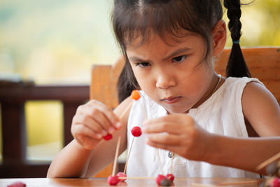 Cute girl making molecule model on wooden table in porch