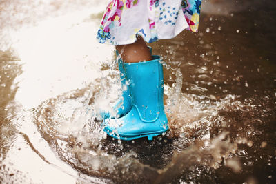 Low section of girl splashing on water