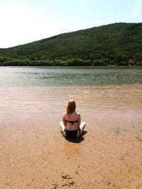 Rear view of woman sitting on beach