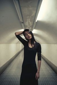 Portrait of young woman standing against wall