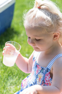 Close-up of cute girl drinking juice in park during sunny day