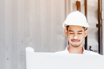 Engineer wearing hardhat reading blueprint outdoors