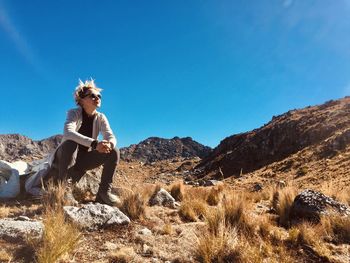 Man standing on rocks against clear blue sky