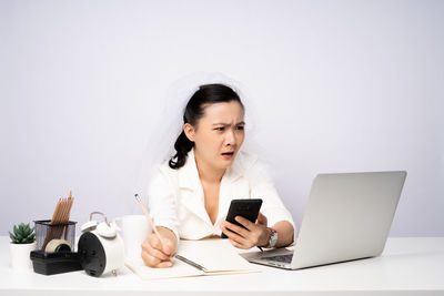 Young woman using mobile phone against white background