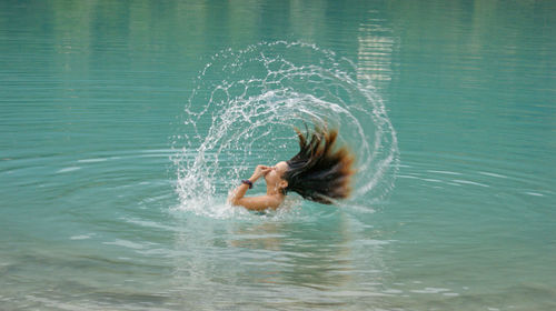 Side view of young woman tossing wet hair in sea