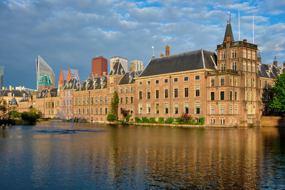 Buildings by river against sky